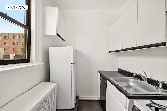 kitchen featuring white cabinets, dishwasher, stove, freestanding refrigerator, and a sink