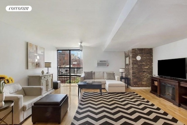 living room with ceiling fan, visible vents, an AC wall unit, floor to ceiling windows, and light wood finished floors