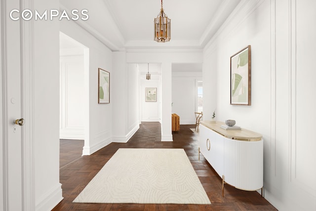 corridor with parquet floors, a chandelier, and a raised ceiling