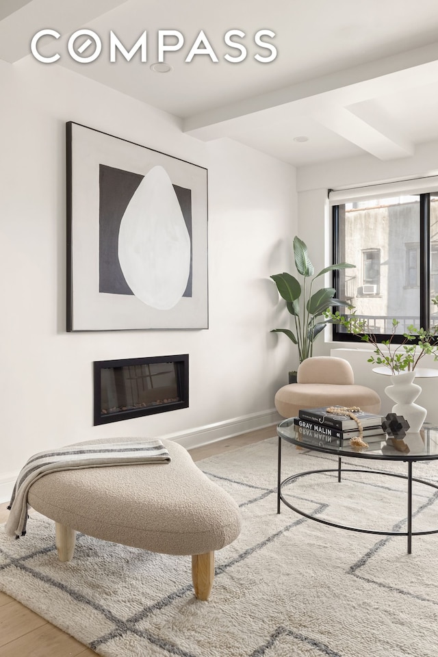 interior space with baseboards, wood finished floors, and a glass covered fireplace