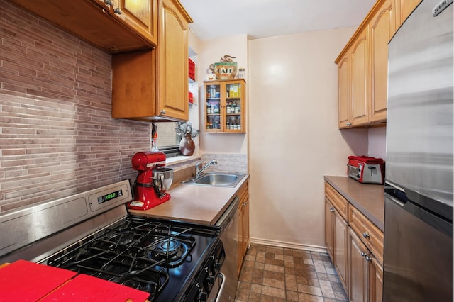 kitchen with baseboards, a sink, decorative backsplash, stone finish floor, and appliances with stainless steel finishes