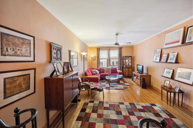 living room with baseboards, wood finished floors, ornamental molding, and a ceiling fan