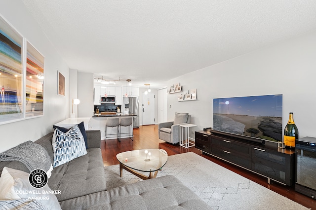 living room featuring a textured ceiling and dark wood-type flooring