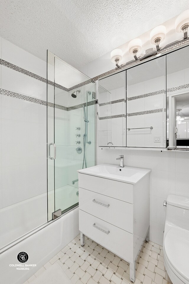 132 E 35th St Unit 11F, New York City, NY 10016 - full bath featuring toilet, enclosed tub / shower combo, vanity, a textured ceiling, and tile patterned floors