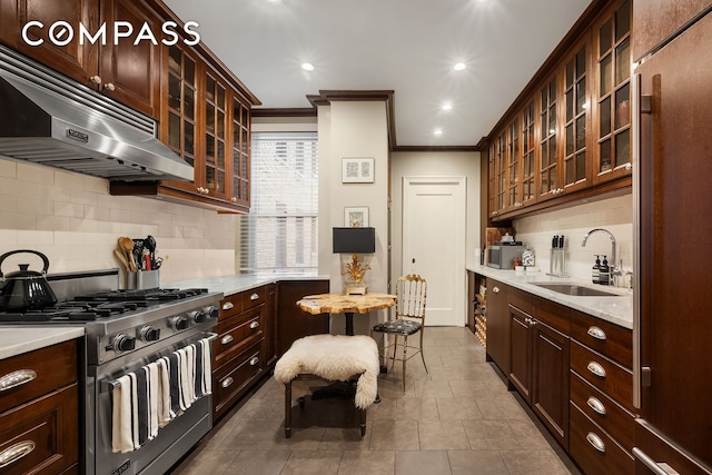 kitchen featuring stainless steel gas range, ornamental molding, a sink, light countertops, and under cabinet range hood