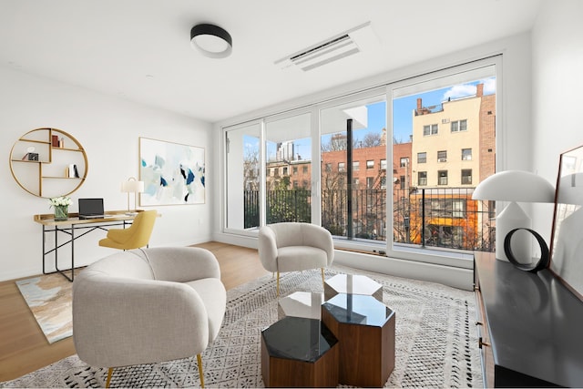 living area with wood finished floors, visible vents, and baseboards