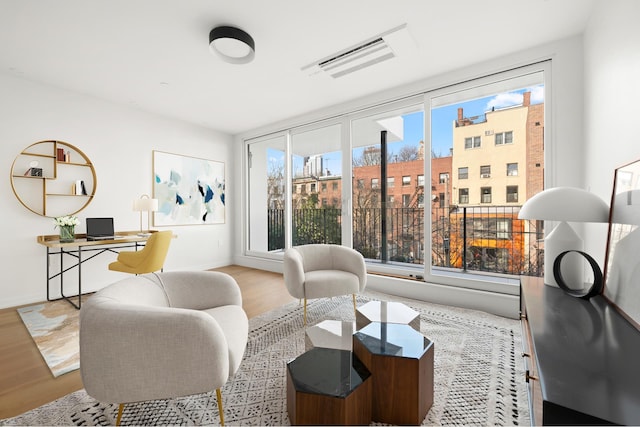 living area featuring visible vents, baseboards, and wood finished floors