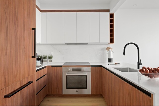 kitchen with light countertops, oven, a sink, and modern cabinets