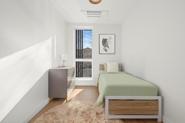 bedroom featuring wood finished floors, visible vents, and baseboards