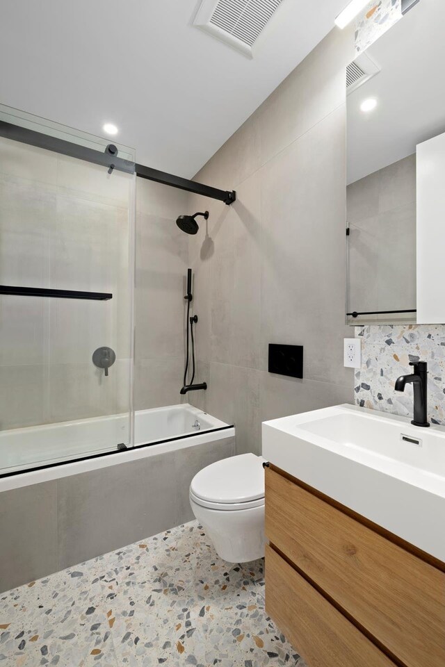 bathroom with shower / bath combination with glass door, toilet, tile walls, visible vents, and vanity