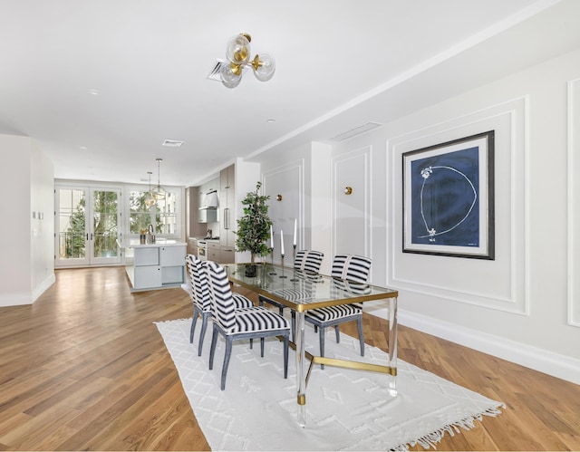 dining room with baseboards, french doors, an inviting chandelier, and light wood-style floors