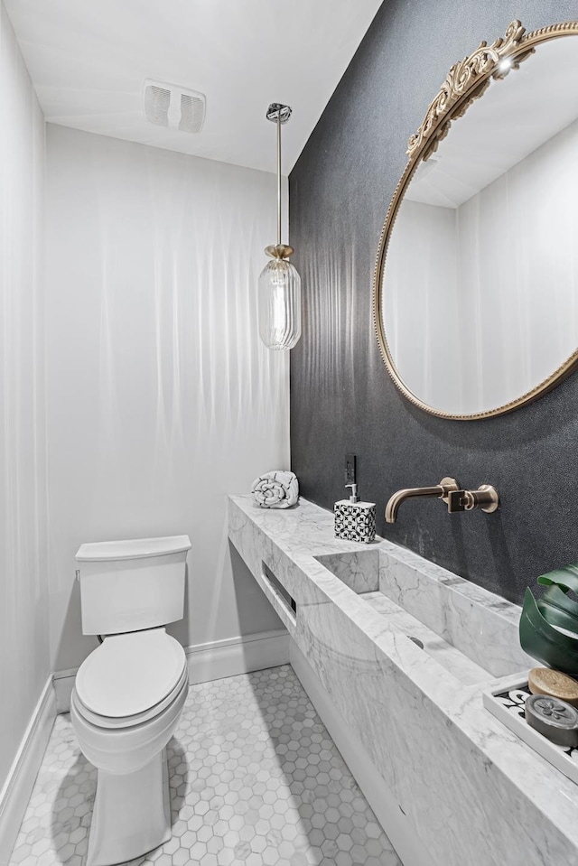 bathroom with baseboards, visible vents, a sink, and toilet