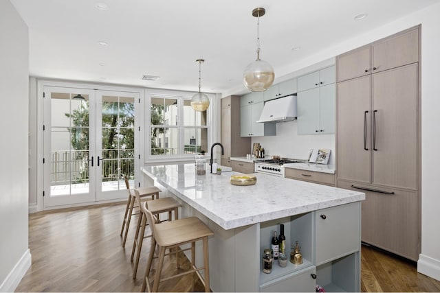 kitchen featuring paneled fridge, under cabinet range hood, a sink, wood finished floors, and white gas range