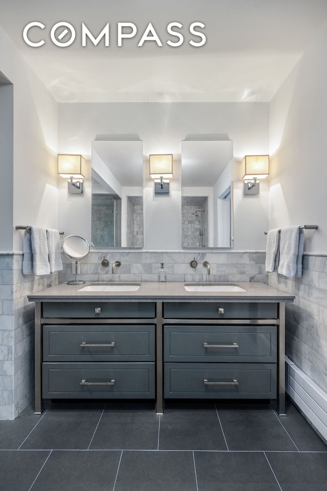 full bathroom with tile walls, tile patterned floors, double vanity, and wainscoting