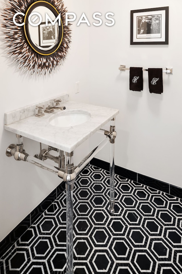 bathroom with tile patterned flooring, a sink, and baseboards