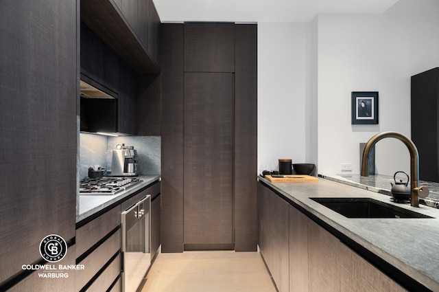 kitchen featuring wall oven, a sink, decorative backsplash, modern cabinets, and stainless steel gas stovetop