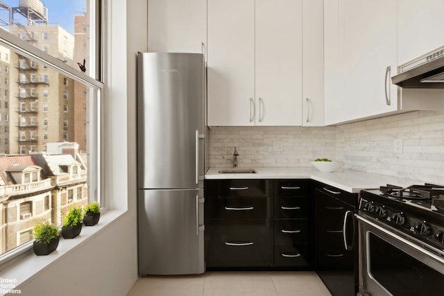 kitchen with stainless steel appliances, a sink, white cabinets, light countertops, and tasteful backsplash