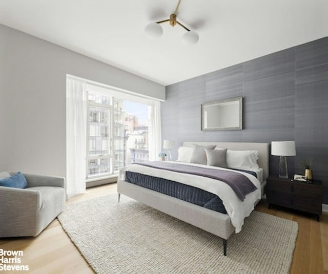 bedroom featuring wood finished floors and an accent wall