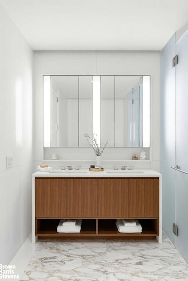 bathroom featuring a sink, marble finish floor, and double vanity