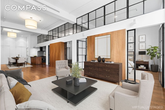 living area with beamed ceiling, wood finished floors, and a towering ceiling