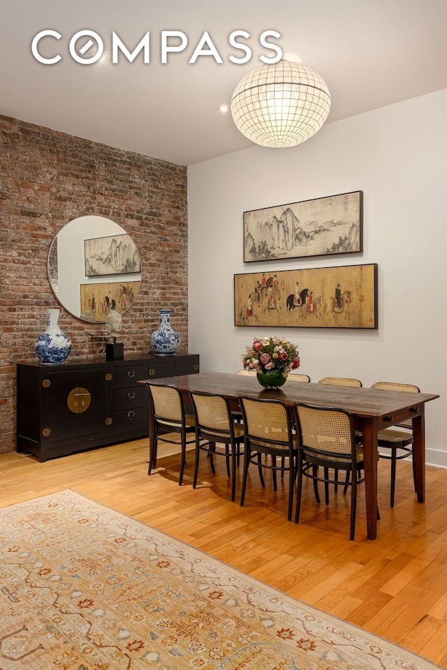 dining area featuring brick wall and light wood-style floors