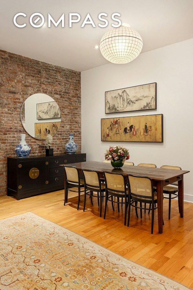 dining area with wood finished floors and brick wall