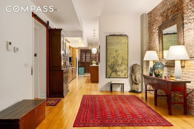 hallway featuring light wood-type flooring and a barn door