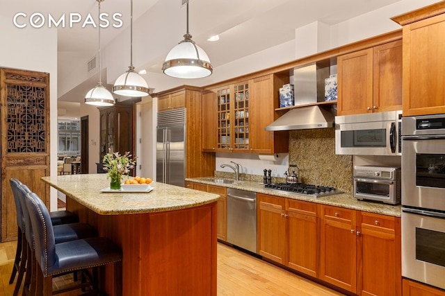 kitchen with a breakfast bar area, a center island, light stone countertops, brown cabinets, and stainless steel appliances