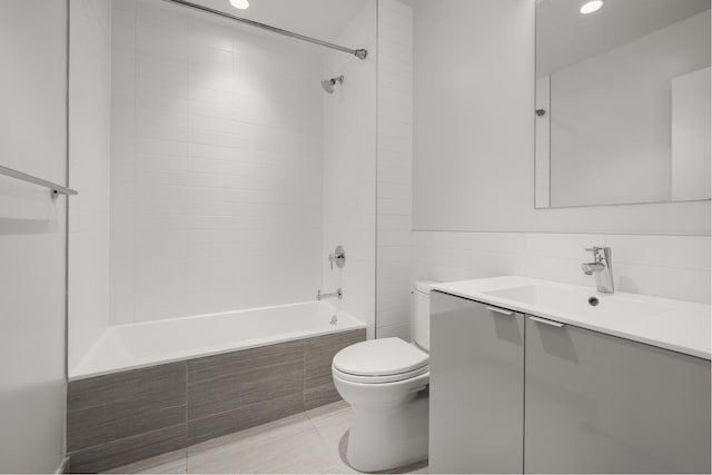 bathroom featuring toilet, tile patterned flooring, vanity, and tiled shower / bath combo