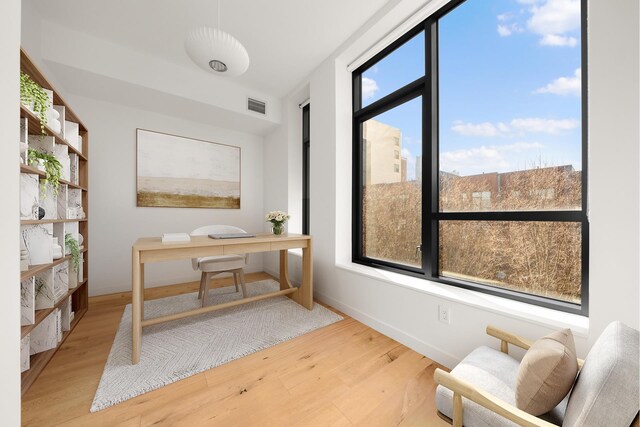 office space featuring wood finished floors, visible vents, and baseboards