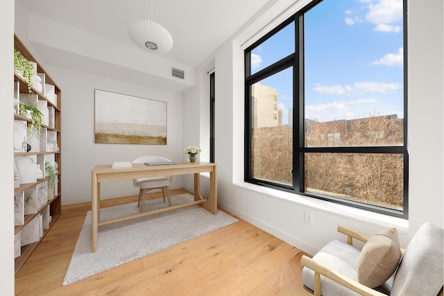 home office with baseboards, wood finished floors, and visible vents