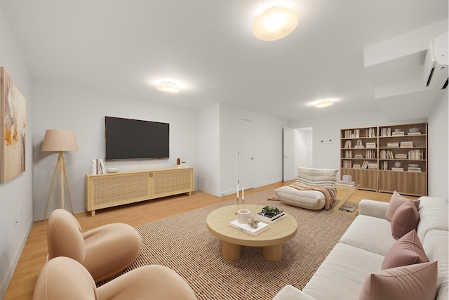 living room with built in features, baseboards, a wall mounted AC, and wood finished floors