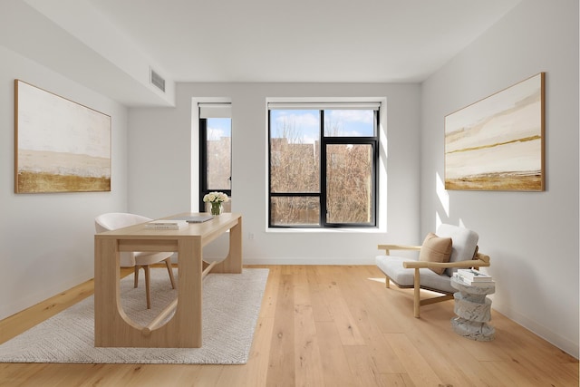 office area with light wood-type flooring, baseboards, and visible vents