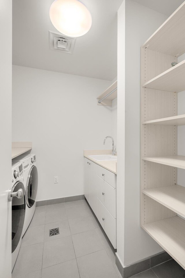 laundry area with baseboards, a sink, light tile patterned floors, and washing machine and clothes dryer