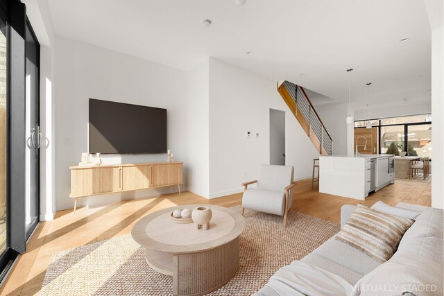 living area featuring light wood finished floors, stairway, and baseboards