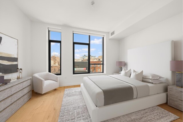 bedroom featuring visible vents, light wood finished floors, and baseboards