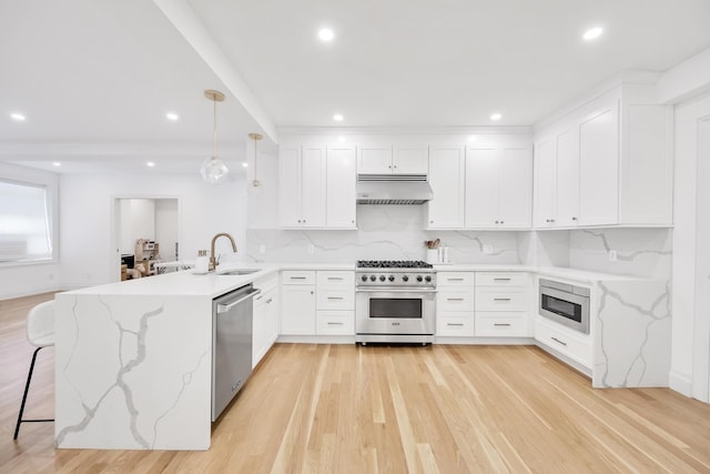 kitchen with tasteful backsplash, under cabinet range hood, a peninsula, stainless steel appliances, and a sink