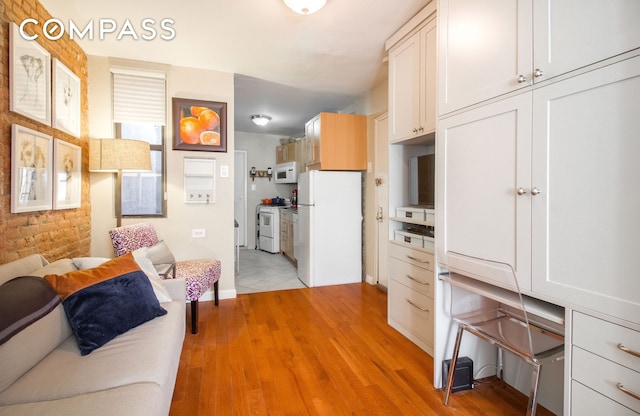 kitchen with white appliances, open floor plan, light wood-type flooring, and brick wall