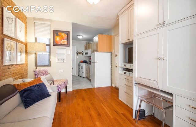 kitchen with white appliances, light wood-style flooring, open floor plan, and baseboards