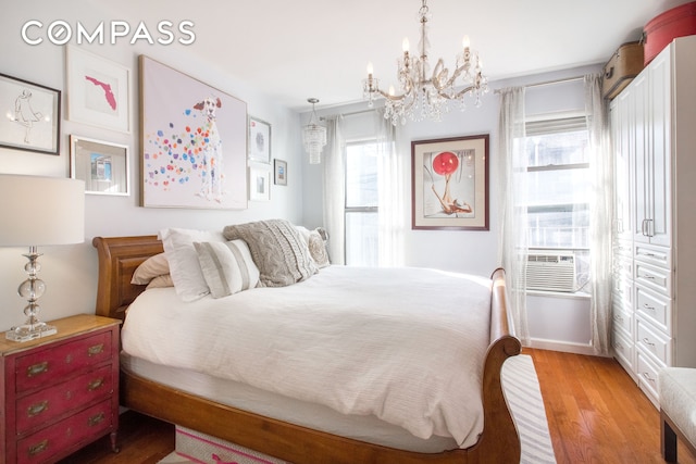 bedroom featuring multiple windows, light wood finished floors, and a chandelier