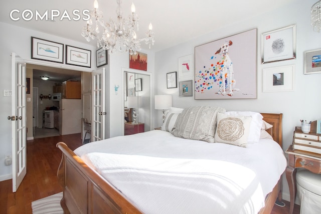 bedroom featuring french doors, a closet, a chandelier, wood finished floors, and freestanding refrigerator