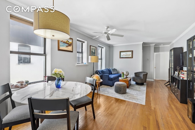 dining space with a ceiling fan, light wood finished floors, and ornamental molding