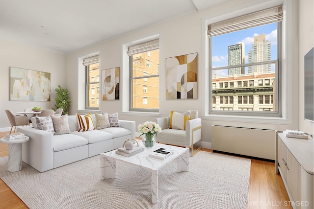 living area featuring crown molding, light wood-type flooring, and baseboards