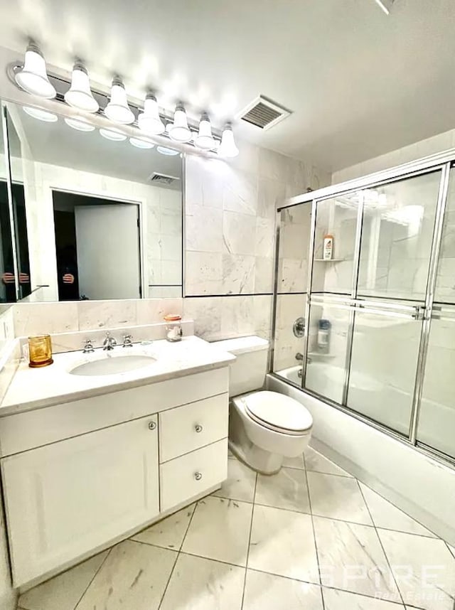 full bath featuring shower / bath combination with glass door, vanity, visible vents, and tile walls