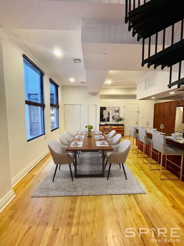 dining room with light wood-type flooring, visible vents, and baseboards