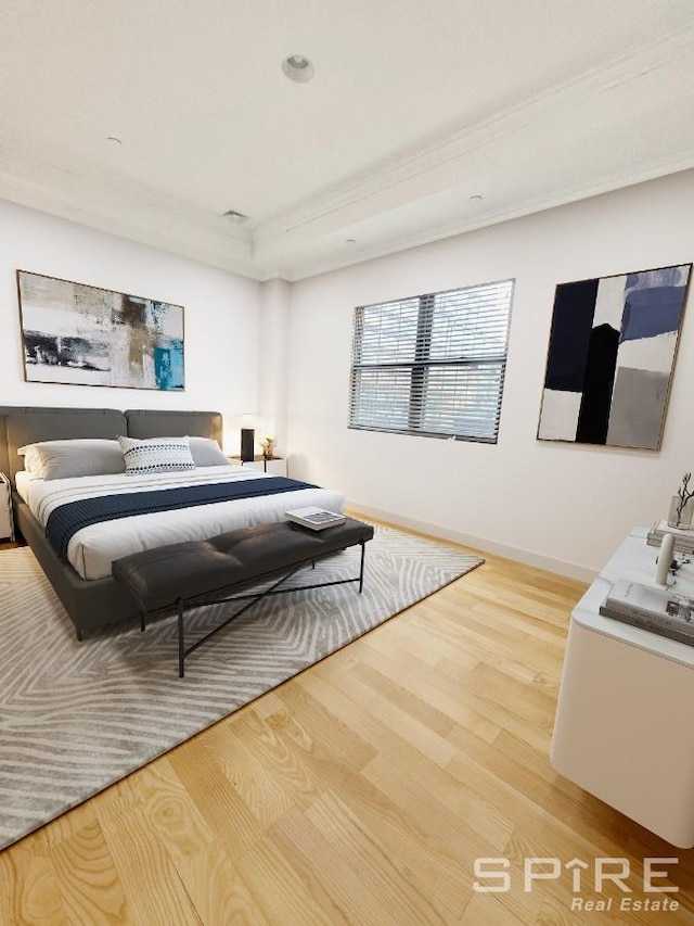 bedroom featuring a raised ceiling, baseboards, and wood finished floors