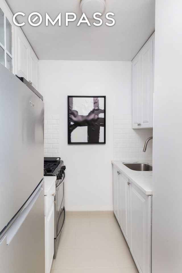 kitchen featuring a sink, backsplash, stainless steel appliances, white cabinets, and light countertops