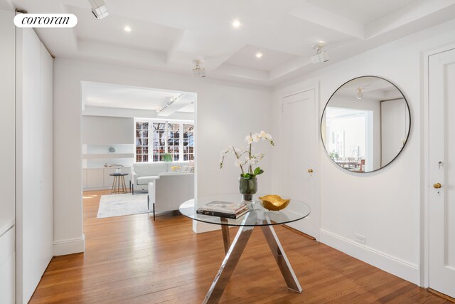 hall with visible vents, coffered ceiling, wood finished floors, and beamed ceiling