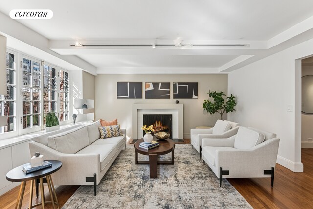 living area featuring wood finished floors, visible vents, baseboards, and a lit fireplace