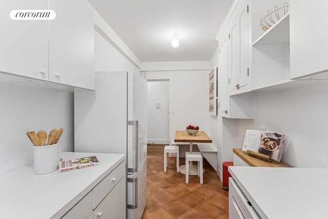 kitchen featuring open shelves, light countertops, freestanding refrigerator, and white cabinetry